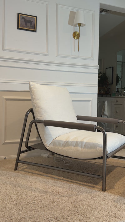 Video showing the aton chenille lounge chair with white cushions, a curved stainless steel frame, and leather-wrapped armrests.