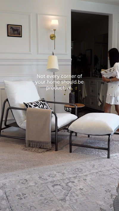 Product video showing a person reading in the aton chenille lounge chair with matching ottoman, featuring a cushioned seat and back, curved stainless steel frame, and leather accents.